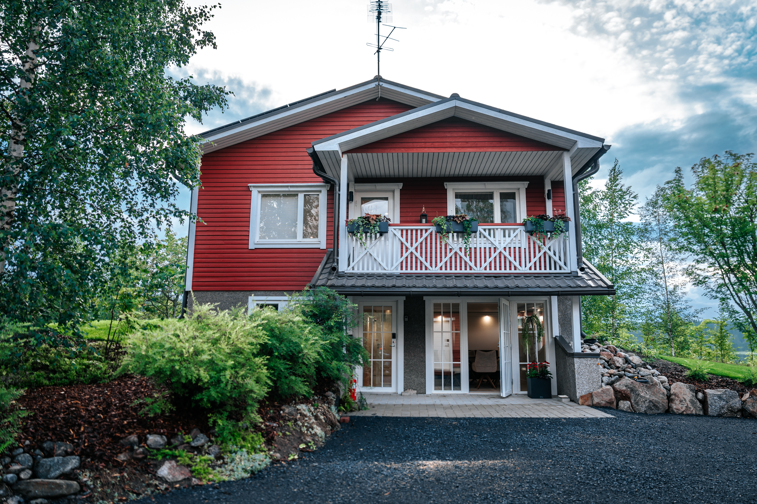 Red two-storey Finnish-style cottage surrounded by trees